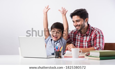 Cute Indian boy with father or male tutor doing homework at home using laptop and books - online schooling concept Royalty-Free Stock Photo #1825380572