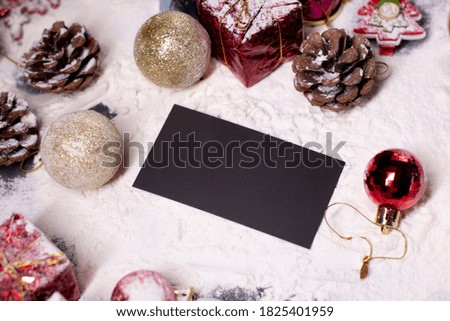 black business card next to New Year's decorations in the snow. Christmas trees, balls, snowflakes, gifts, cones. Christmas mood. Flatly photo. 
