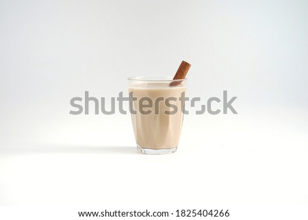 front view of hot masala chai or Indian spices tea in a transparent glass and cinnamon stick on white background Royalty-Free Stock Photo #1825404266