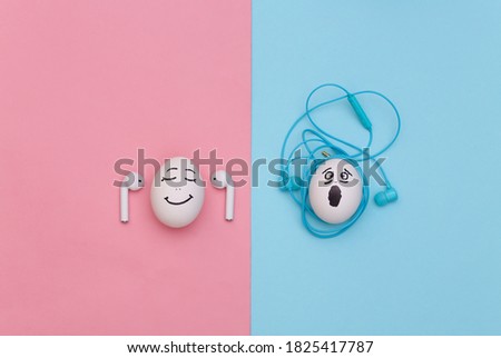 Humorous concept. Eggs with faces listening to music with wireless and wired tangled headphones. Modern technologies. Blue and pink background. Flat lay