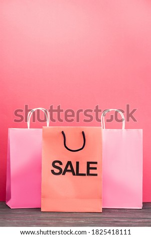 shopping bag with sale lettering near paper packets on pink, black friday concept