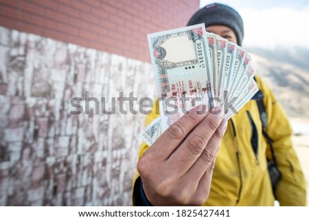 An unidentified man showing a pile of Nepalese money (thousand rupees banknotes). Conceptual of Nepal currency banknotes. Royalty-Free Stock Photo #1825427441