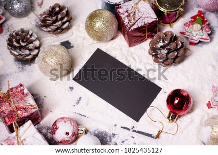 black business card next to New Year's decorations in the snow. Christmas trees, balls, snowflakes, gifts, cones. Christmas mood. Flatly photo. 