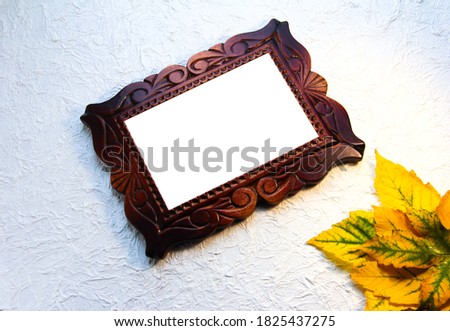 Wooden frame on a white crumpled background with yellow leaves.