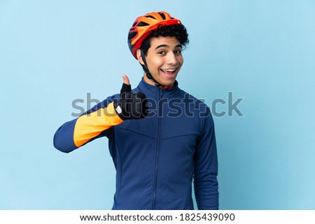 Venezuelan cyclist man isolated on blue background with thumbs up because something good has happened