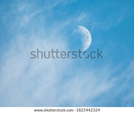 Moon in blue sky among white clouds
