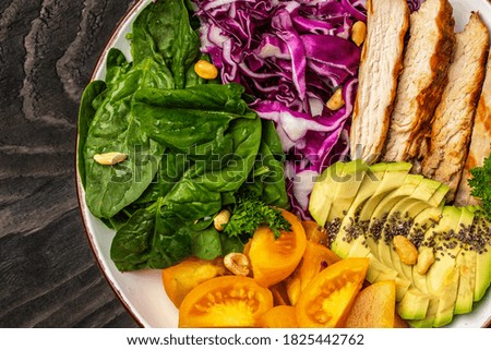 Diet menu. Healthy salad of fresh purple cabbage, avocado, spinach, tomatoes, fillets and nuts on a bowl. Vegan food. Top view.