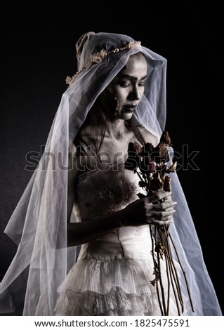 Horror Scene of a Possessed bride Woman in white dress black long hair ghost zombie holding dried Rose Bouquet on hand in dark room isolated. halloween scary concept