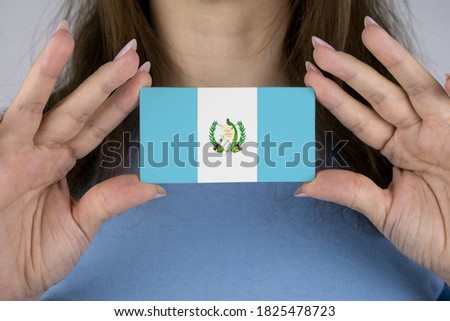 A woman shows a business card with an image of the Guatemala flag.