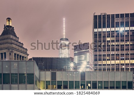Illuminated buildings in New York City financial district at night with lens flares, color toning applied, USA.