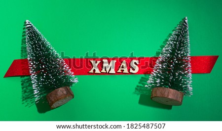 Christmas card. Two Christmas trees with greetings. Red spruce with the words xmas. green background.