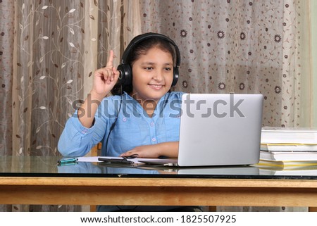 Young Indian girl wearing headset learning through laptop. E- learing concept.