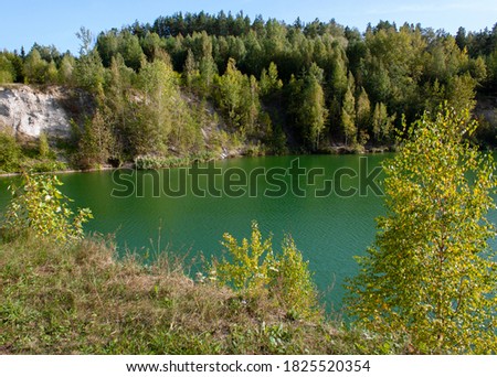 Suburbs of Grodno. Belarus. Green lake. Forest on the shore and its reflection in the water. The sun's rays on the crowns of trees and on the surface of the water.