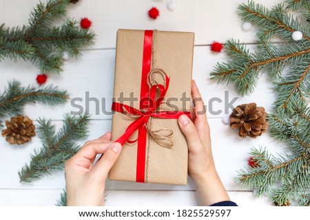 The gift in the hand that opens it on white wooden backgroun decorated with spruce branches, pine cones, New Year's toys.Christmas and New Year concept. Top view, flat lay 