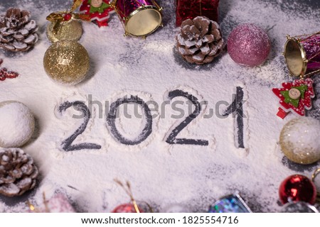 New Year's decorations, decorative elements - in the snow. Christmas trees, balls, snowflakes, gifts, cones. Finger-drawn '2021' in the snow. Christmas mood. Flatly photo.