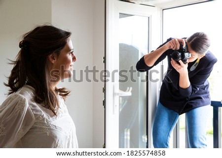 A professional make up artist at work, taking photograph of woman.