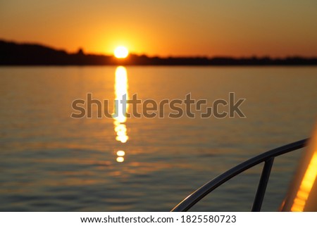 View from yacht railing on beautiful blurred sunset, bright orange sunshine with reflection track in calm water on forest on Horizon background at Sunny summer evening, scenery relax photo picture 
