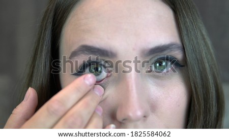 Close-up of a beautiful lady putting a lens in her eye