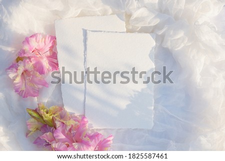 Blank paper card with copy space . Pink gladiolus flower on white textile background. Styled stock photography for display your design, lettering, font, illustration, wedding stationary. Flat lay