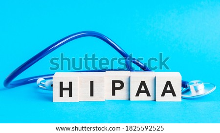HIPAA word made with building blocks. Wooden block with words virus with stethoscope on the table, insurance and medical concept, blue background