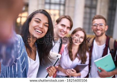 Two girls and two guys with notebooks in their hands are smiling at the camera for photography.
