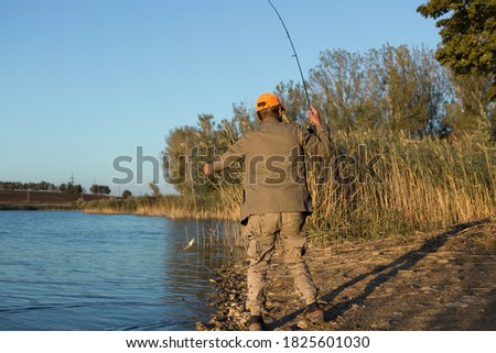 Fisherman standing on the riverside and trying to catch a fish. Sport, recreation, lifestyle.