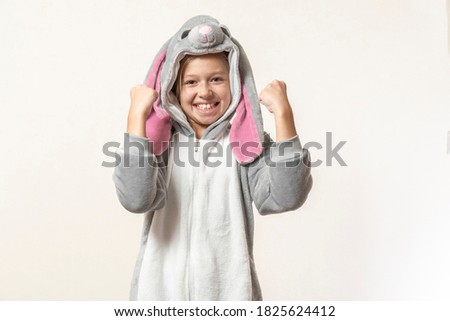 girl in a rabbit costume rejoices on a light background.