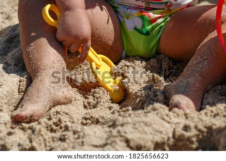 Little girl playing in the sand, close up photo of the sandy legs