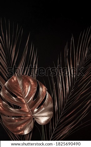 Gold leaf isolated on a black background  top view. Gold palm, monstera leaves , plant frame with copy space. abstract poster.