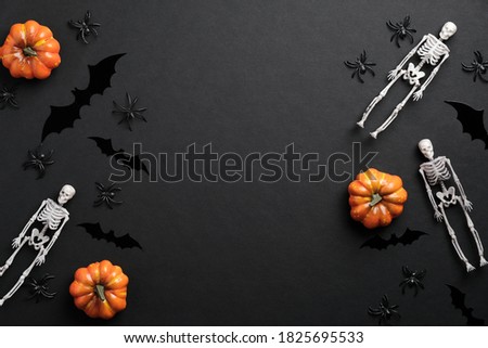 Halloween flat lay composition. Skeletons, pumpkins, spiders, silhouettes of bats on black background. Halloween banner mockup, greeting card template