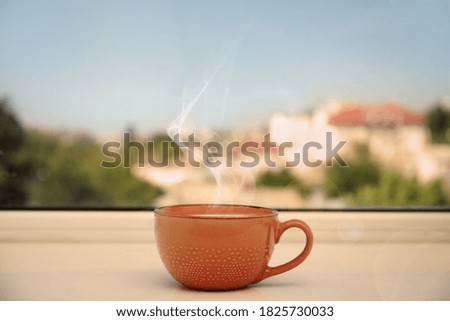 Cup of hot coffee on window sill indoors