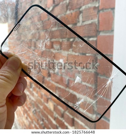 broken protective glass for the smartphone screen in the hand of a phone repairman. Glass replacement repair concept for phones