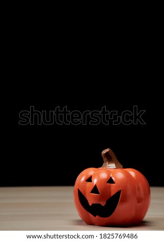 Halloween holiday concept with pumpkin head jack lantern on wooden table with dark background copy space for text