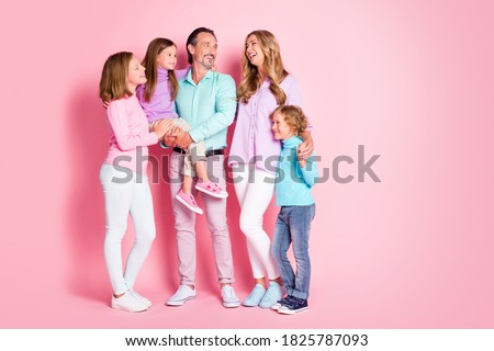 Full size photo of cheerful idyllic family dad hold carry small younger daughter mommy laughing enjoy fun time hold hand son isolated over pastel color background