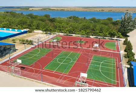 Outdoor sports complex near bay on sunny day, aerial view