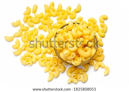 Uncooked raw Italian pipe rigate pasta in a glass bowl on isolated white background. Close up.