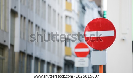 Two red forbidden access signs on the streets of a city