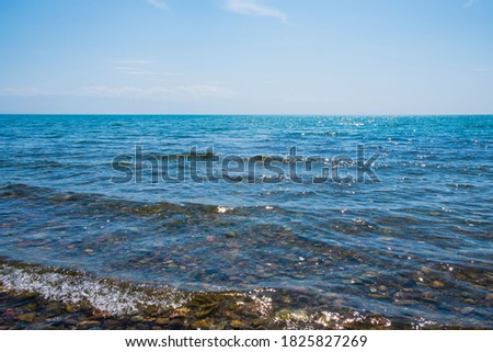 Sea with pebble bottom landscape with blue sky. Summer nature landscape. Summer vacation concept. 
