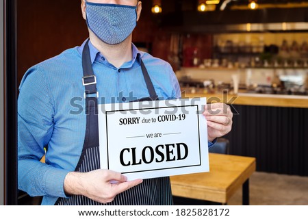 Businessman closing business activity due to covid-19 emergency lockdown quarantine – Owner with protective face mask at restaurant entrance holding closing sign due to coronavirus – Bankruptcy store Royalty-Free Stock Photo #1825828172
