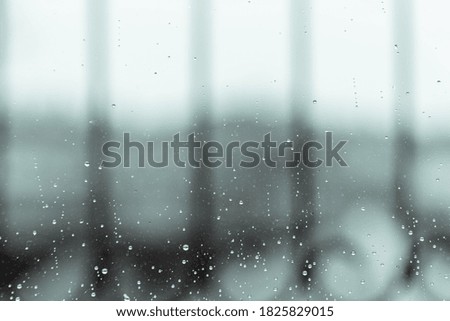 Background of rain water drop on wet window with blurred rooftop view in cold and rainy in winter day