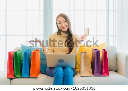 Portrait beautiful young asian woman with laptop computer and credit card for online shopping on sofa in living room