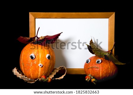 Couple happy pumpkins with eyes and yellow wooden frame, boy and girl, cute lovers. Black background. Thanksgiving, Halloween concept. Copy space, mock-up. 