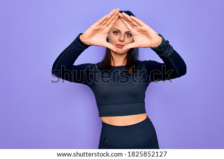 Young beautiful brunette sporty woman wearing casual sportswear over purple background doing frame using hands palms and fingers, camera perspective