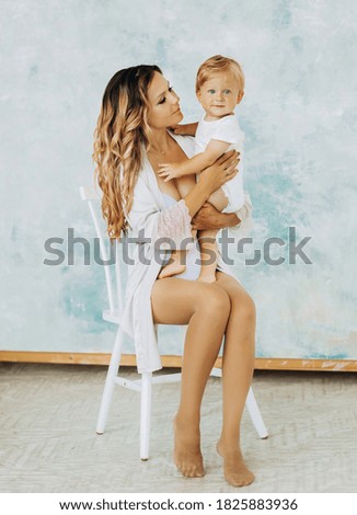 Beautiful mother holds her son on her lap on blue background
