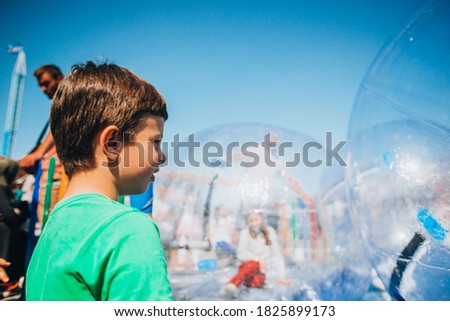 Cute happy kid boy playing in inflatable attraction on playground
