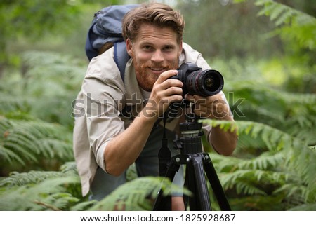 professional photographer shooting with camera on tripod in a forest