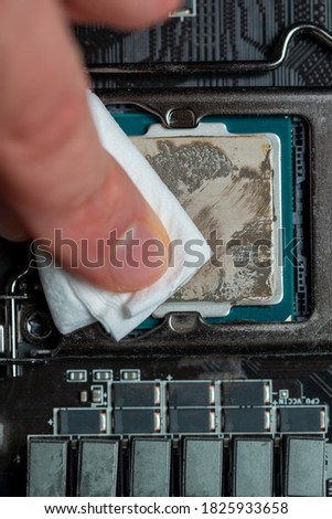 Macro shot of motherboard and Cpu microchip with old thermal paste. Servicing PC and cleaning paste. Blurred finger in motion. Royalty-Free Stock Photo #1825933658