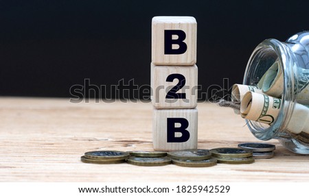 B2B (Business to business) - abbreviation on cubes on the background of a capacity with money. Business and finance concept