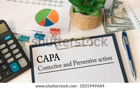 Paper with Corrective and Preventive action CAPA on the table, calculator and money