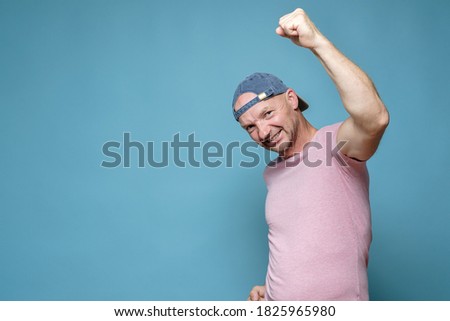 Confident, strong man makes a winner gesture raising hand with a clenched fist up, bares teeth and looks at the camera. Copy space